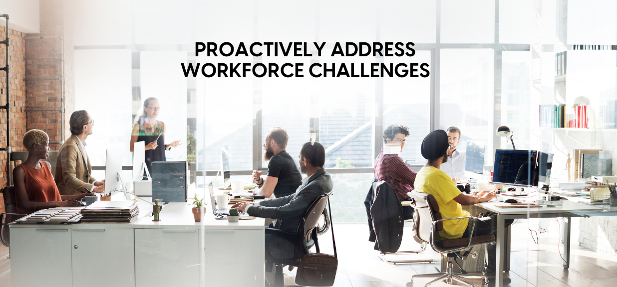 Office with diverse employees working and engaging in a discussion about proactively addressing workforce challenges through effective payroll management.
