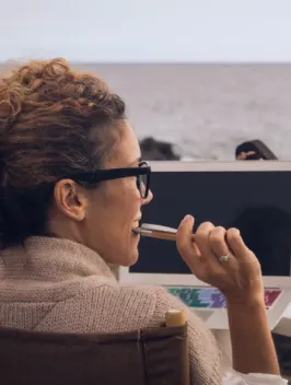 A woman in a cozy sweater wearing with a computer monitor displaying Global payroll & EOR solutions.