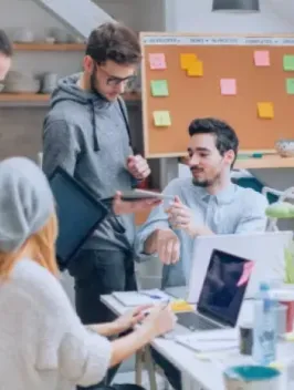 A dynamic office scene with four young professionals engaged in a technology-enabled discussion. Highlighting Neeyamo payroll tech solutions.